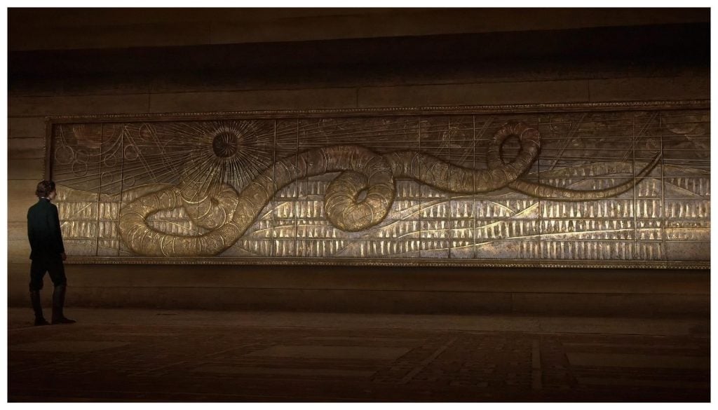 Timothée Chalamet with a golden relief artwork of a giant sandworm in <em>Dune</em>, directed by Denis Villeneuve. Photo courtesy of Legendary Entertainment and Warner Bros. Pictures.