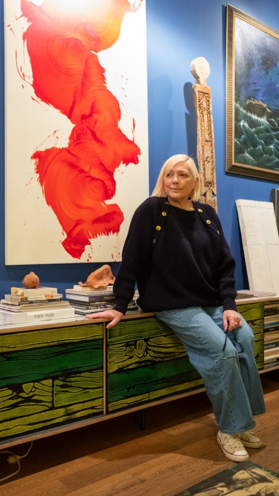 Gina Nanni with Jamie Nares, Untitled (2005), and in the background an African work from the estate of Fred Hughes; a painting by Robert Hawkins, Jesus Waterskiing, and a Richard Prince “Protest” painting. The clay nose sculpture is by Peter Nadin. Courtesy Gina Nanni.