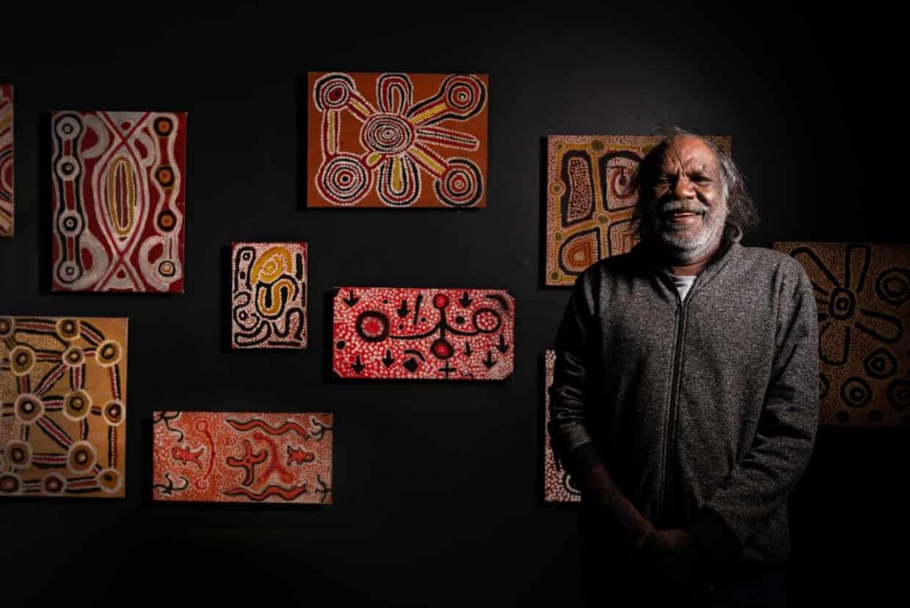 Gary Njamme, one of the only surviving original Balgo artists with his work at "Balgo Beginnings" at the South Australian Museum. Photo by Brad Griffin, courtesy of the South Australian Museum, Adelaide. 