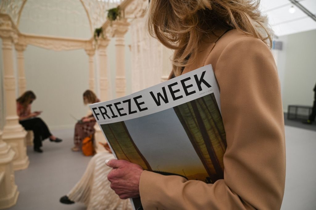An attendee holds the Frieze Week Magazine on the first day of Frieze Los Angeles, a leading international art fair, February 17, 2022 in Beverly Hills, California. Photo by ROBYN BECK/AFP via Getty Images.