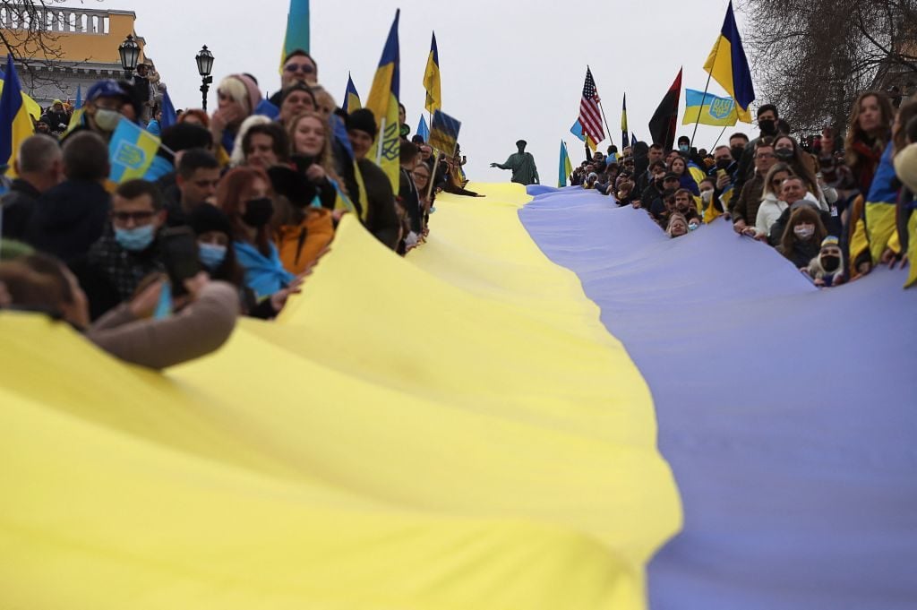 Protesters carry a giant Ukrainian flag during a rally to show unity and support of Ukrainian integrity, amid soaring tensions with Russia, in the southern Ukrainian city of Odessa, on February 20, 2022. Photo: Oleksandr Gimanov/AFP via Getty Images.