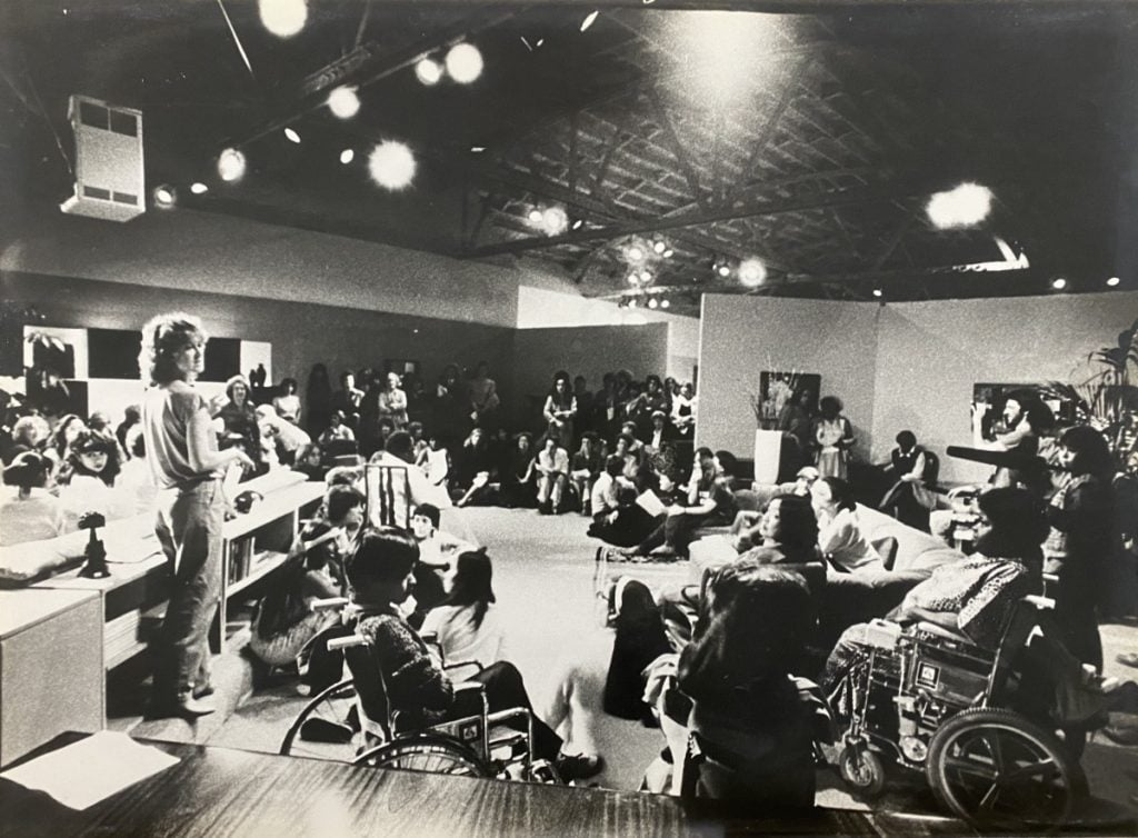 Suzanne Lacy and Julia London with Jan Chattler, Joya Cory, Natalia Rivas, Ngoh Spencer, and Carol Szego, <em>Freeze Frame: Room for Living Room</em> (1982), performance view, Roche Bobois furniture showroom, San Francisco. Photo by f-stop Fitzgerald, courtesy of Suzanne Lacy Studio.