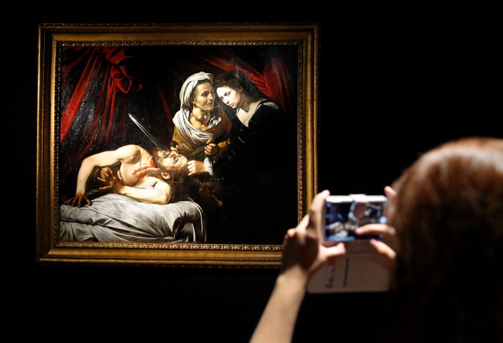 A visitor takes a photo of the painting 'Judith decapitating Holofernes' (1607) by Caravaggio at the Drouot auction house on June 14, 2019 in Paris, France.  Photo by Chesnot/Getty Images.