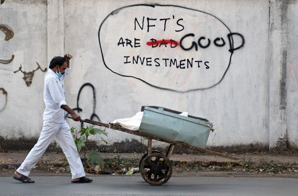A scrap dealer in India pushes his handcart past NFT graffiti. (Photo by Ashish Vaishnav/SOPA Images/LightRocket via Getty Images)