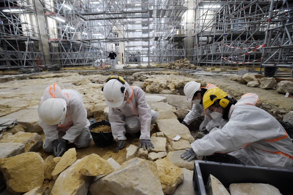 Archaeologists excavate the floor of Notre Dame Cathedral after the discovery of a 14th century lead sarcophagus, in Paris, on March 15, 2022. Photo by Julien de Rosa/AFP via Getty Images.
