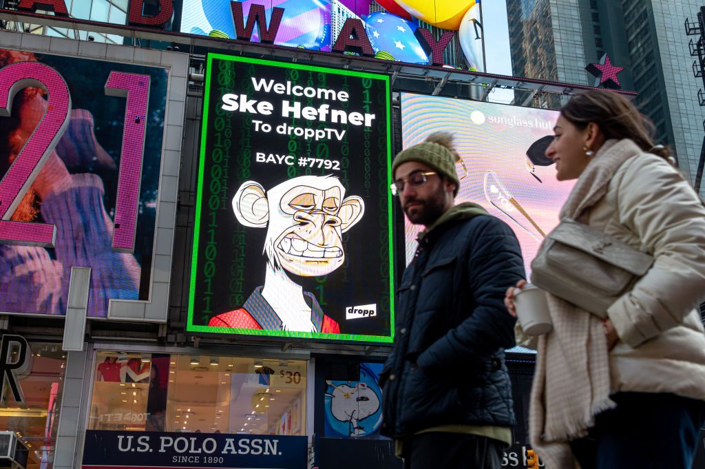 People walk by a Bored Ape Yacht Club NFT billboard in Times Square on January 25, 2022 in New York City. (Photo by Noam Galai/Getty Images)