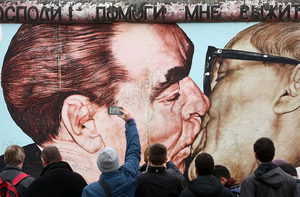 Visitors photograph graffiti by Dmitri Vrubel of General Secretary of the Communist Party of the Soviet Union Leonid Brezhnev and East German General Secretary of the Socialist Unity Party Erich Honecker kissing on East Side Gallery, a section of the former Berlin Wall, during celebrations for the 25th anniversary of the fall of the Wall on November 9, 2014 in Berlin, Germany. (Photo by Adam Berry/Getty Images)