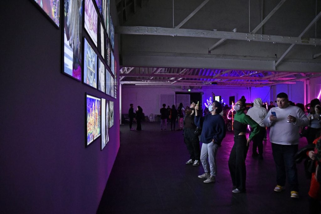 A group of people look at digital NFT art at the FRIEZE Week NFT event for 