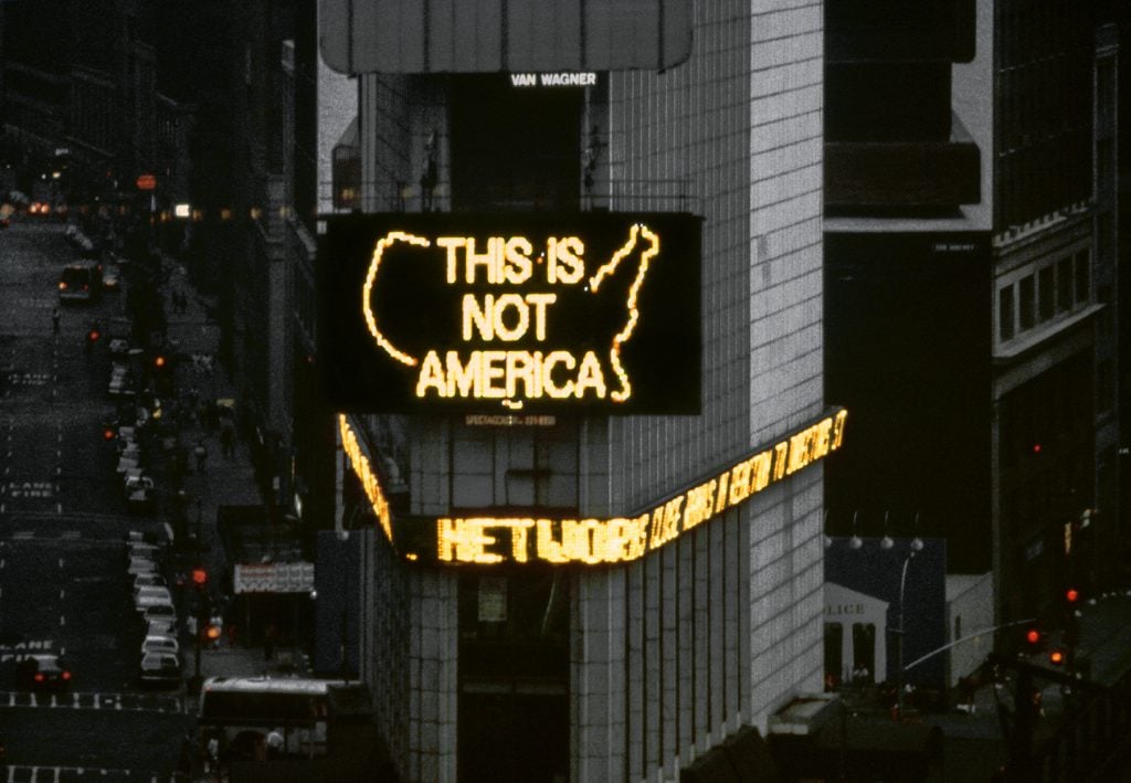 ألفريدو جار ، <em></noscript> logotipo para américa </ em> (1987) de "mensajes al público," Fondo de Arte Público, Times Square, Nueva York.  Fotografía: el artista.  » width=»1024″ height=»709″ srcset=»https://news.artnet.com/app/news-upload/2022/04/AJ_A-LOGO-FOR-AMERICA_1987-1024×709.jpg 1024w, https:/ /news.artnet.com/app/news-upload/2022/04/AJ_A-LOGO-FOR-AMERICA_1987-300×208.jpg 300w, https://news.artnet.com/app/news-upload/2022/04/ AJ_A-LOGO-FOR-AMERICA_1987-50×35.jpg 50w» size=»(max-width: 1024px) 100vw, 1024px»/></p>
<p class=