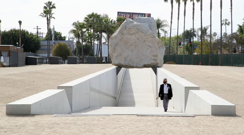 LOS ANGELES, CALIFORNIA - APRIL 26: A guard wearing a protective face mask walks through Michael Heizer"s "Levitated Mass" at the Los Angeles County Museum of Art during the coronavirus pandemic on April 26, 2020 in Los Angeles, California. COVID-19 has spread to most countries around the world, claiming over 206,000 lives with more than 2.9 million confirmed cases. (Photo by David Livingston/Getty Images)
