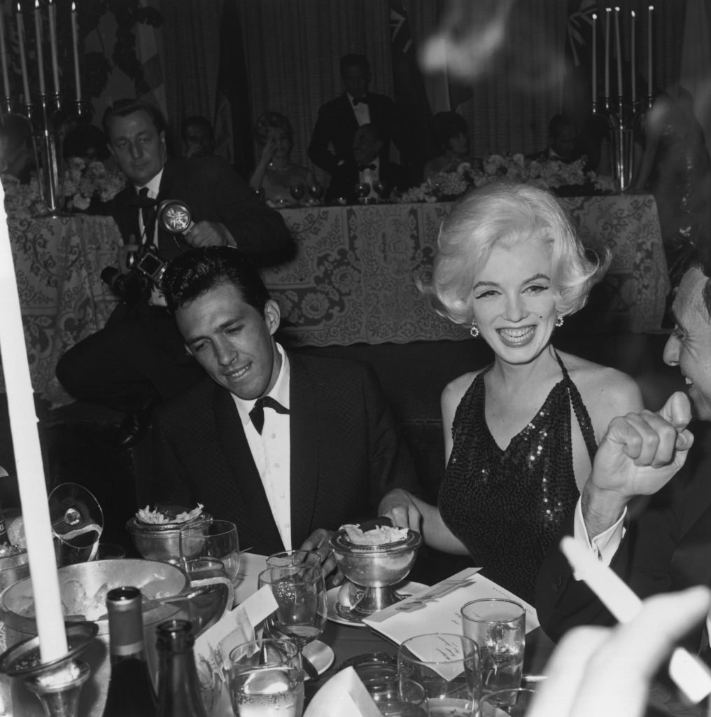 Marilyn Monroe and writer Jose Bolanos sit at a dining table during the Golden Globes. Photo by Hulton Archive/Getty Images