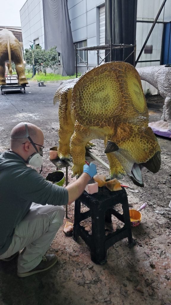 Эндрю Мейнер рисует аниматронную статую динозавра в зоопарке Бронкса. "сафари динозавр" Выставка.  Фотография Эндрю Майнира.