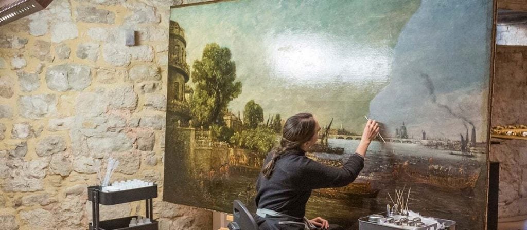 A conservator at work on John Constable's largest known painting of Waterloo Bridge in 1817. Photo: James Dobson, courtesy National Trust.
