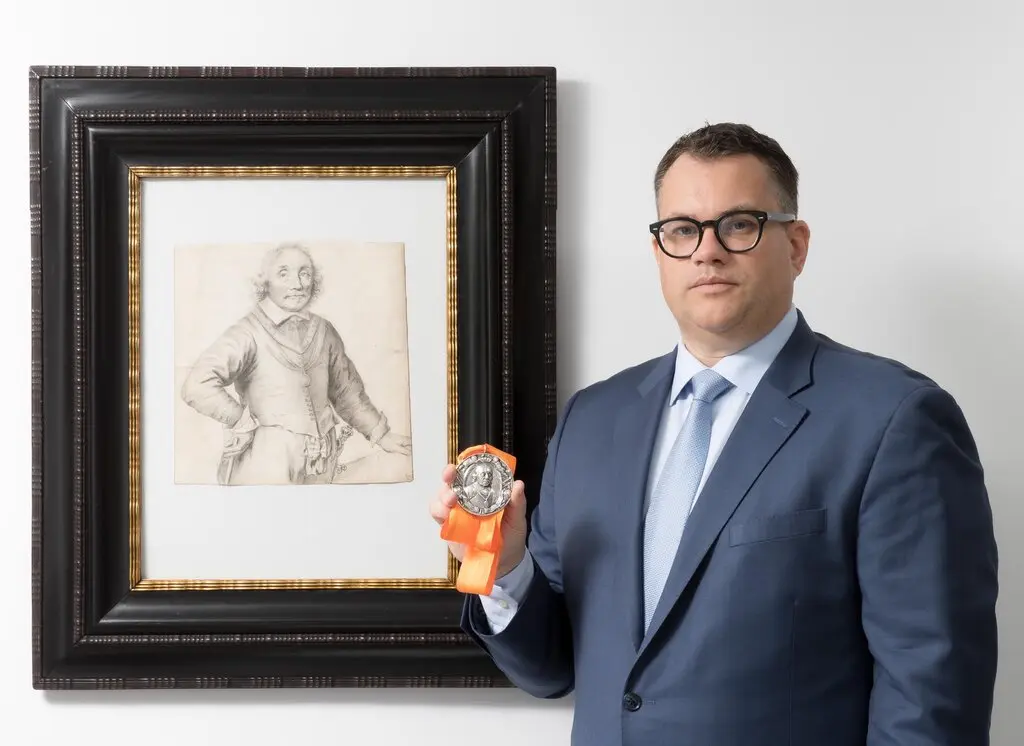 Christopher Bishop with Jan Lievens's <em>Portrait of Admiral Maarten Harpertszoon Tromp (1597–1653)</em>, ca. 1652/53, and a 17th-century silver commemorative medal depicting the admiral. Photo courtesy of Christopher Bishop Fine Art, New York. 