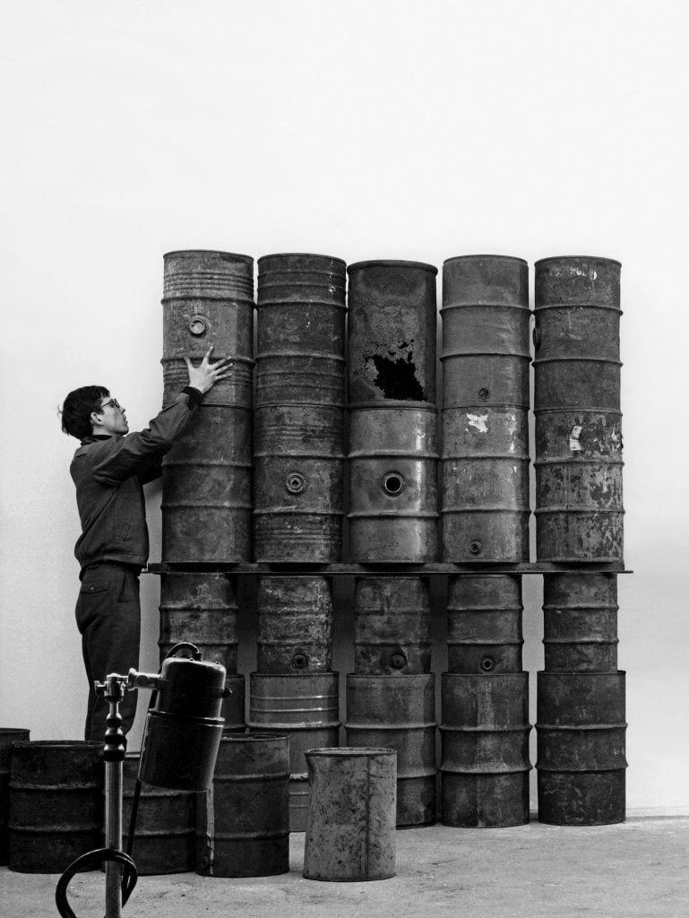 Paris, 1961: Christo during the erection of 26 Oil Barrels (1961) in the studio of photographer Jean-Dominique Lajoux Artwork © Christo and Jeanne-Claude Foundation Photo: Jean-Dominique Lajoux Image courtesy Gagosian