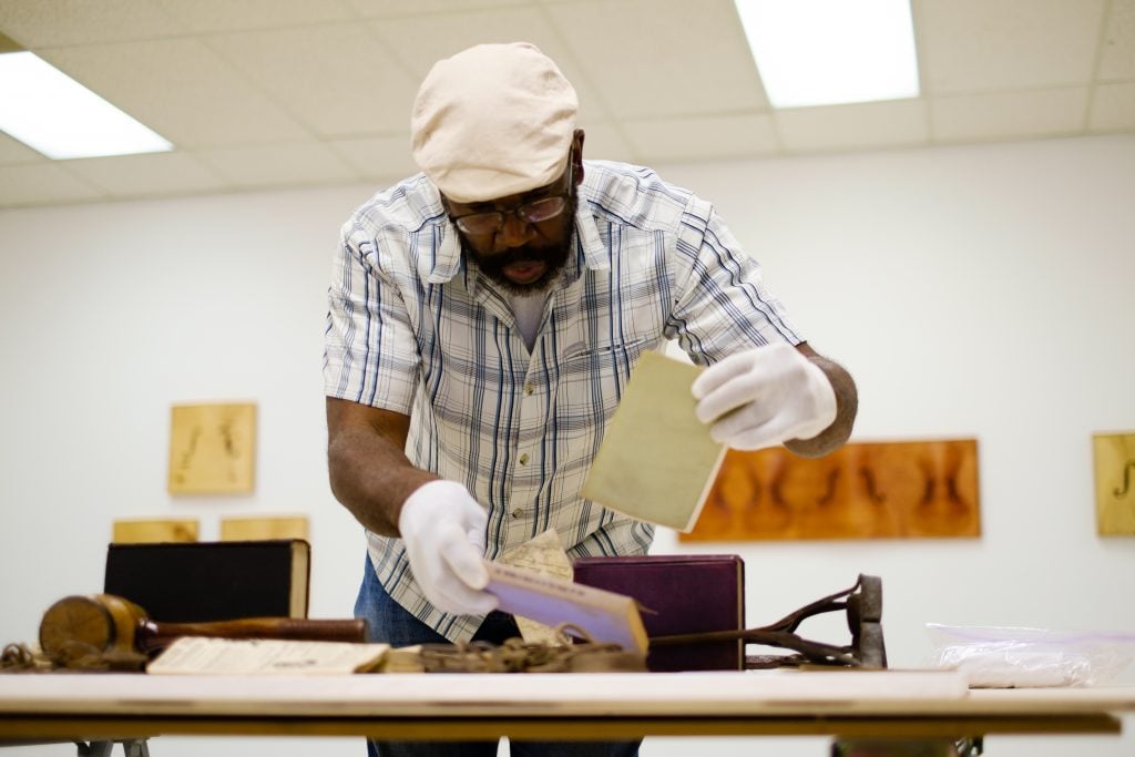 Artist Paul Rucker places racist artifacts for display during installation of 