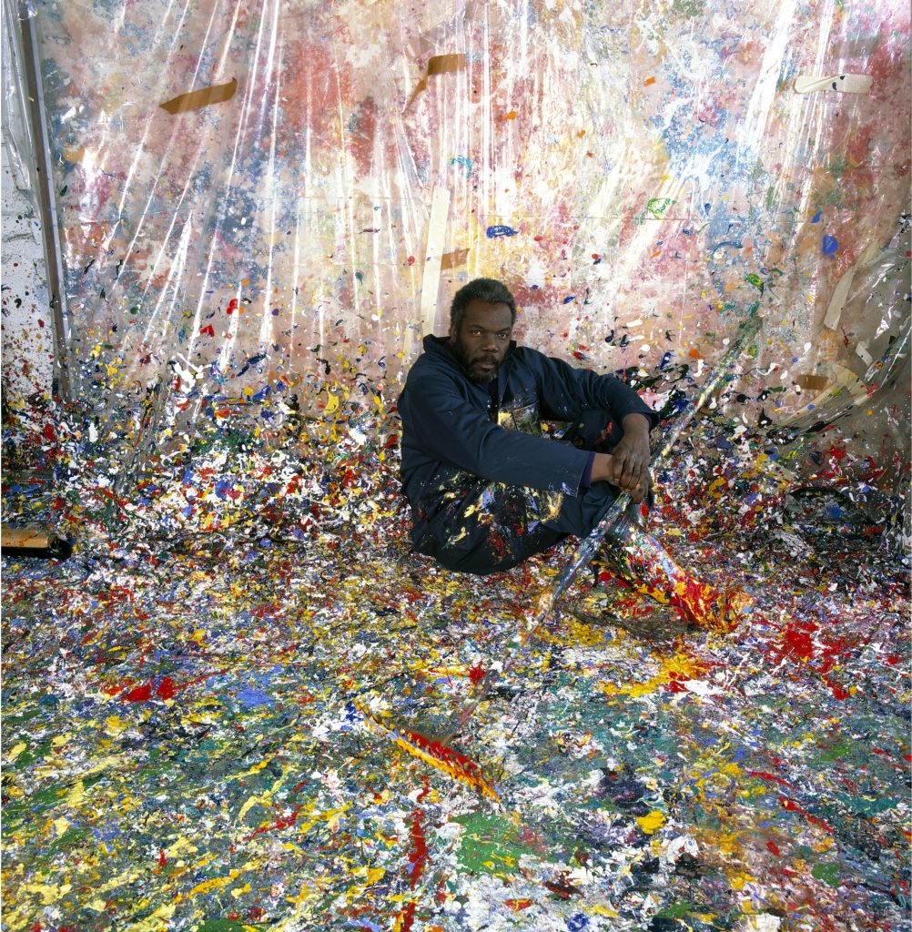 Portrait of African American painter Sam Gilliam, seated on the floor of his paint splattered studio, Washington, DC, 1980. (Photo by Anthony Barboza/Getty Images)