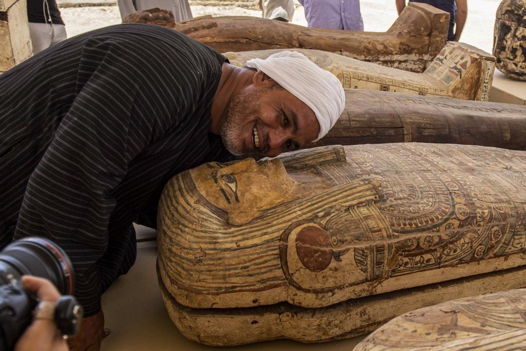 A member of the excavation team poses next to a wooden sarcophagus discovered at the Saqqara necropolis, southwest of Egypt's capital. Photo by Khaled Desouki/AFP via Getty Images.