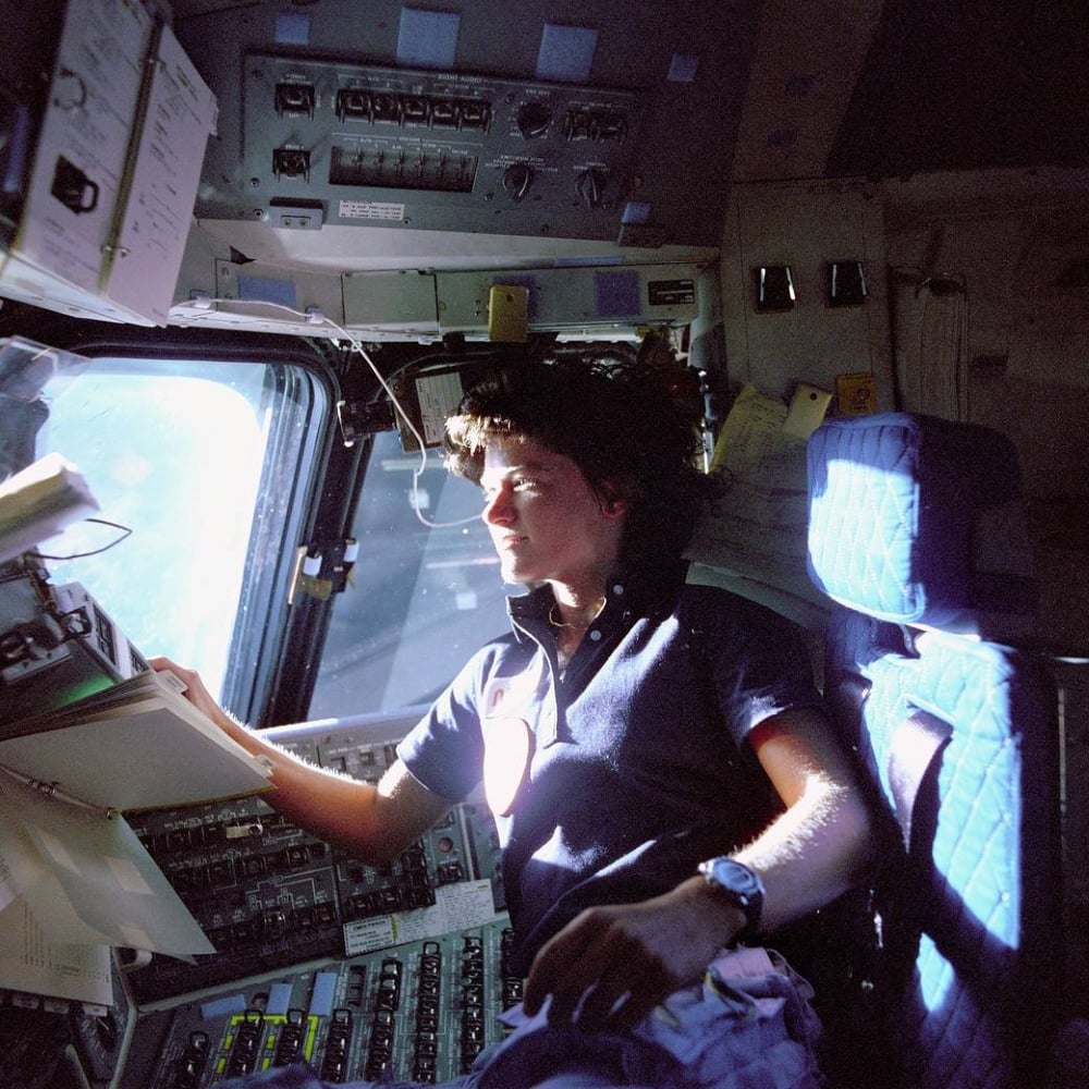 Sally Ride, the first U.S. woman to go to space, monitoring control panels from the pilot's chair on the flight deck during the Space Shuttle Challenger's STS-7 mission in 1983. Photo courtesy of NASA.