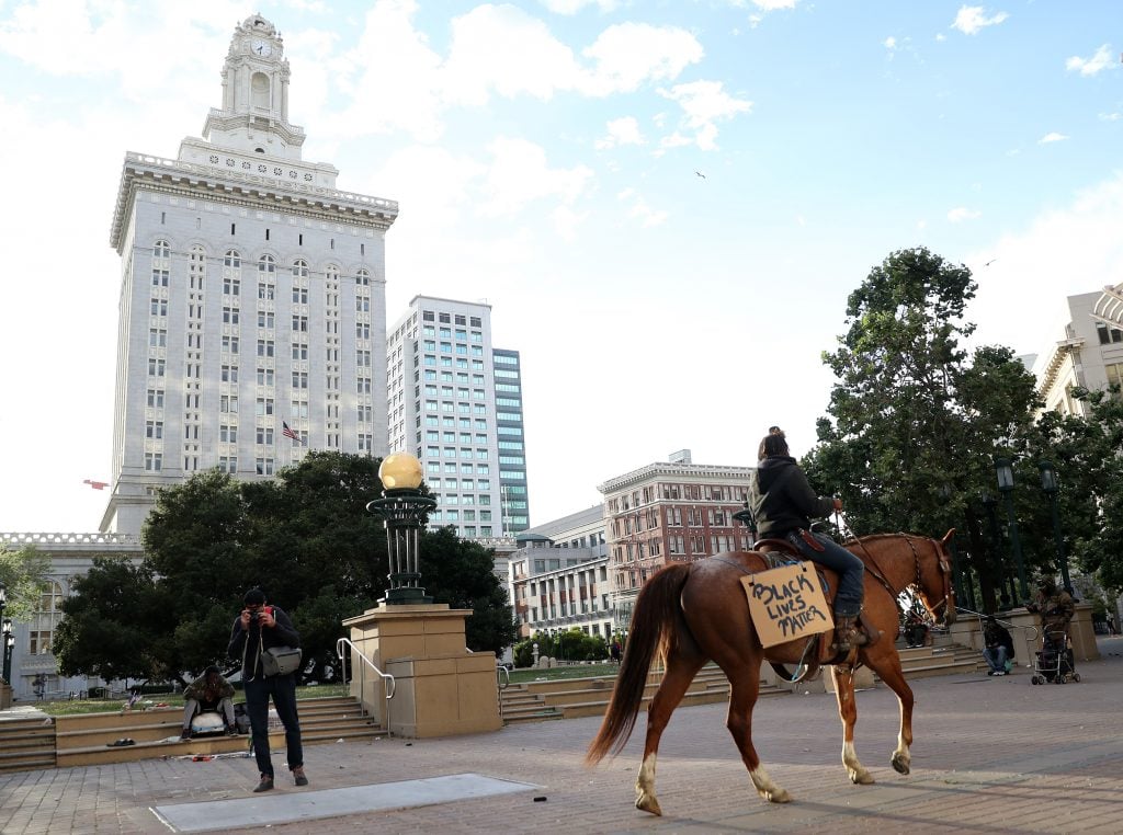 Brianna Nobel rides her horse named Dapper Dan wearing a sign that reads "Black Lives Matter" during a protest in Oakland, California, sparked by the death of George Floyd at the hands of Minneapolis police officer Derek Chauvin. Photo by Justin Sullivan/Getty Images.