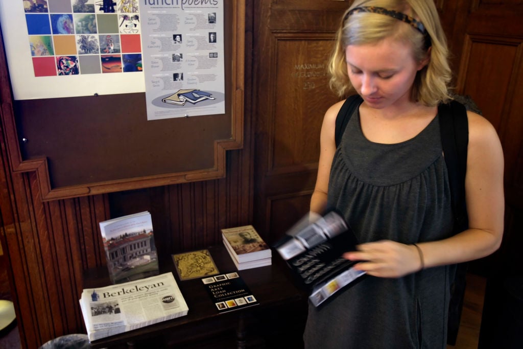 A UC Berkeley student looks at a brochure for the university's Graphic Art Loan Collection, which allows students, faculty, and staff to borrow original framed artwork for up to one year.  (Photo by Carlos Avila Gonzalez/The San Francisco Chronicle via Getty Images)