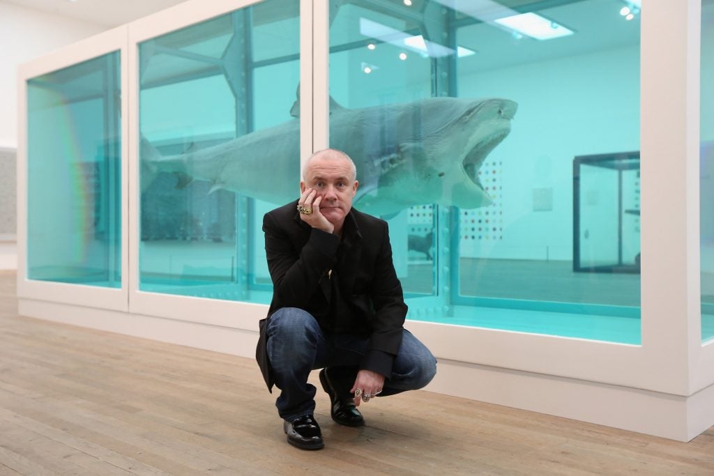 Damien Hirst poses with The Physical Impossibility of Death in the Mind of Someone Living at Tate Modern in 2012. Photo by Oli Scarff/Getty Images.