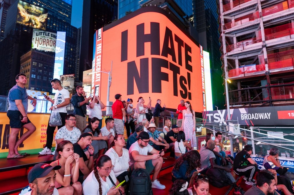 A sign says "I hate NFTs" at the NFT.NYC conference