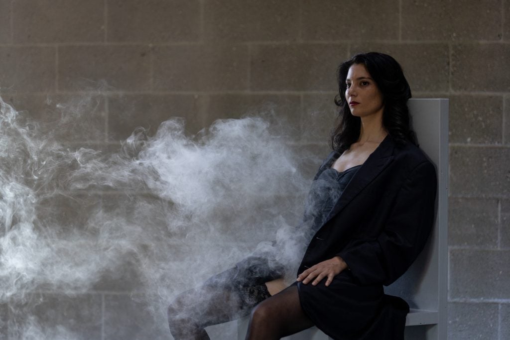 Gokcen Dilek Acay is smoking "Forms of protest" performance.  Photo by Maria Baranova, courtesy of Pelham Communications. 