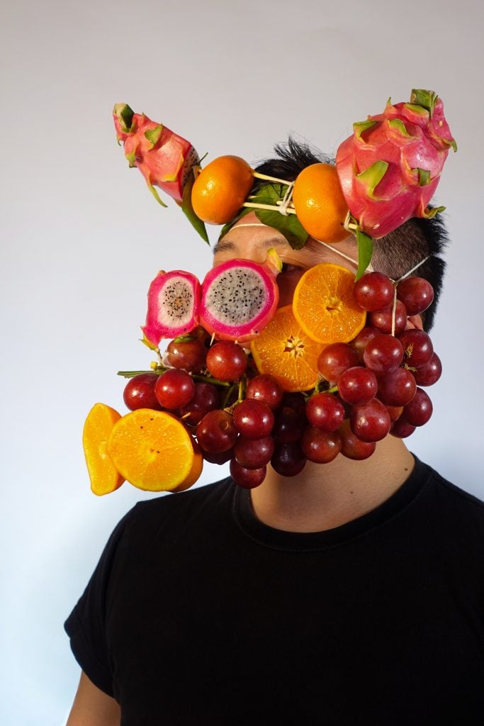 Foodmasku, Antonius Oki Wiriadjaja, wears “Good Fortune Fruit Mask.” Courtesy of the artist.