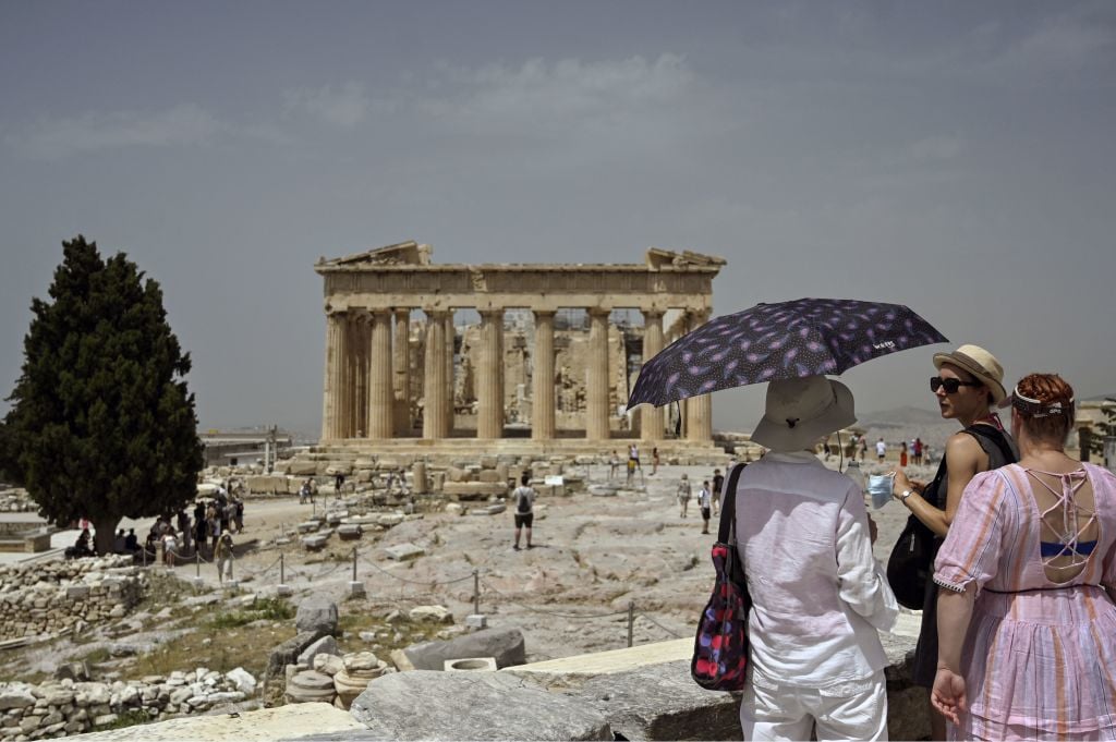 A tourist holds a parasol as she visits the Ancient Acropolis archeological site in Athens on July 1, 2021. Photo by LOUISA GOULIAMAKI/X07402/AFP via Getty Images.