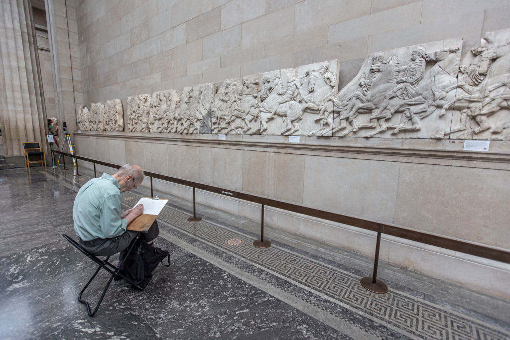 A man as seen painting in front of the Parthenon Marbles at the British Museum. Photo by Nicolas Economou/NurPhoto via Getty Images.