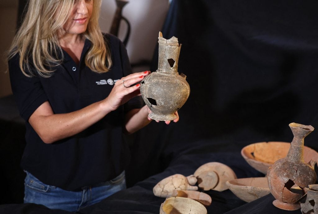 An employee at the Israel Antiquities Authority holds one of the vessels that are believed to have contained opium some 3,300 years ago, found at the Tel Yehud burial site. Photo by Ahmad Gharabli/AFP via Getty Images.