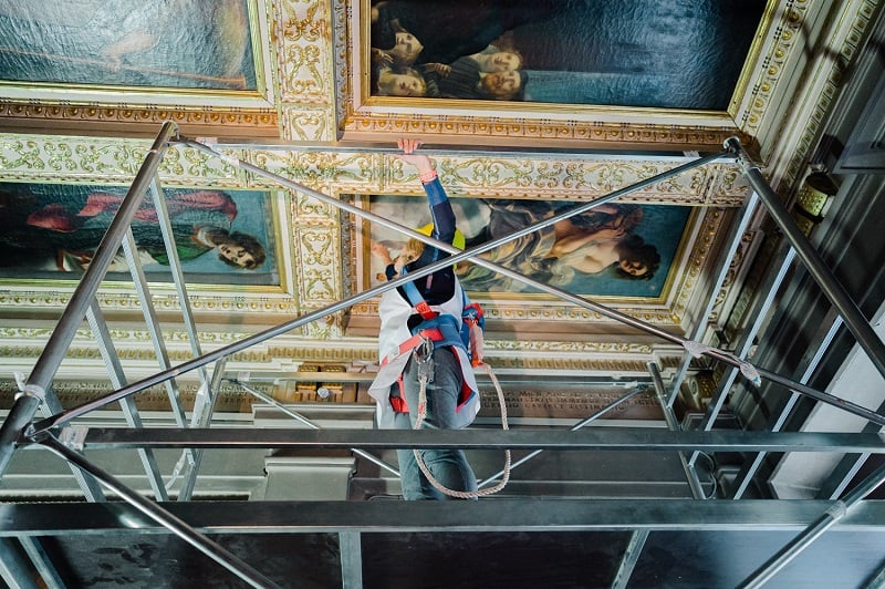 Curator Elizabeth Wicks examines Artemisia Gentileschi, Allegory of the Inclination (1816) before its removal from the ceiling of the Casa Buonarroti, Florence.  Photo by Olga Makarova, courtesy of Casa Buonarroti, Florence.