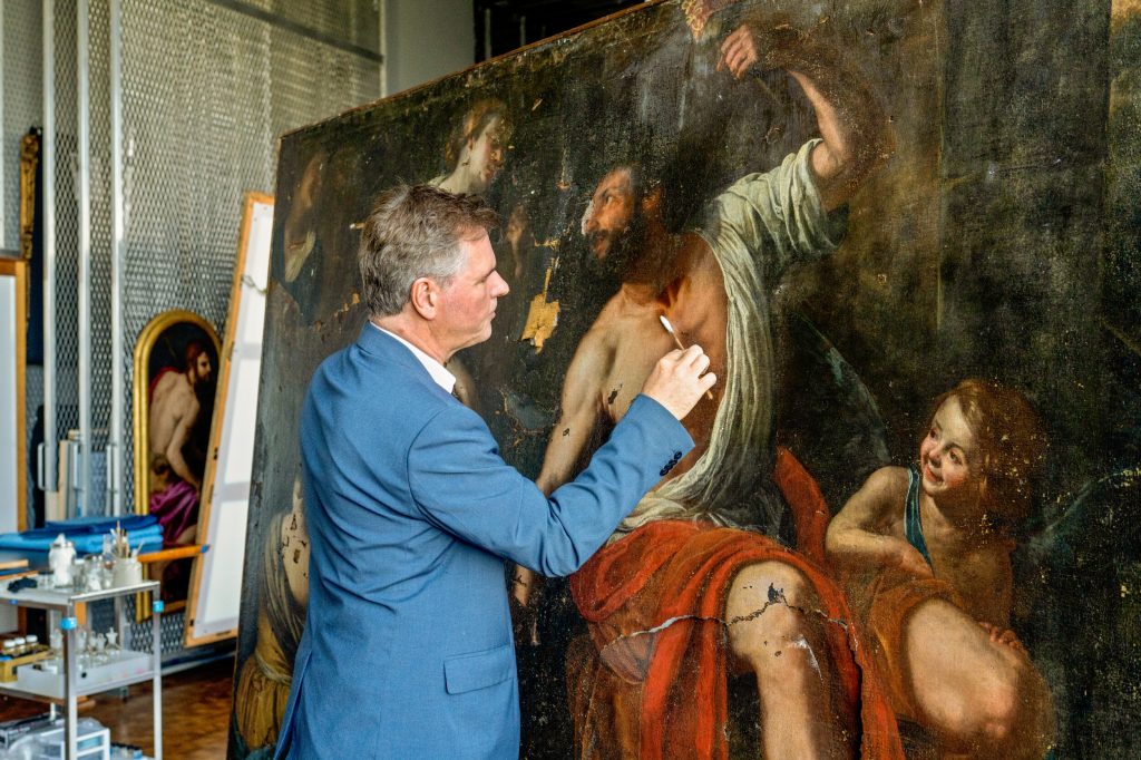 Ulrich Birkmaier uses a swab in the restoration of Artemisia Gentileschi's Hercules and Omphale at the J Paul Getty Museum in Los Angeles. Photo by Cassia Davis., ©2022 J. Paul Getty Trust / Sursock Palace Collections, Beirut, Lebanon.