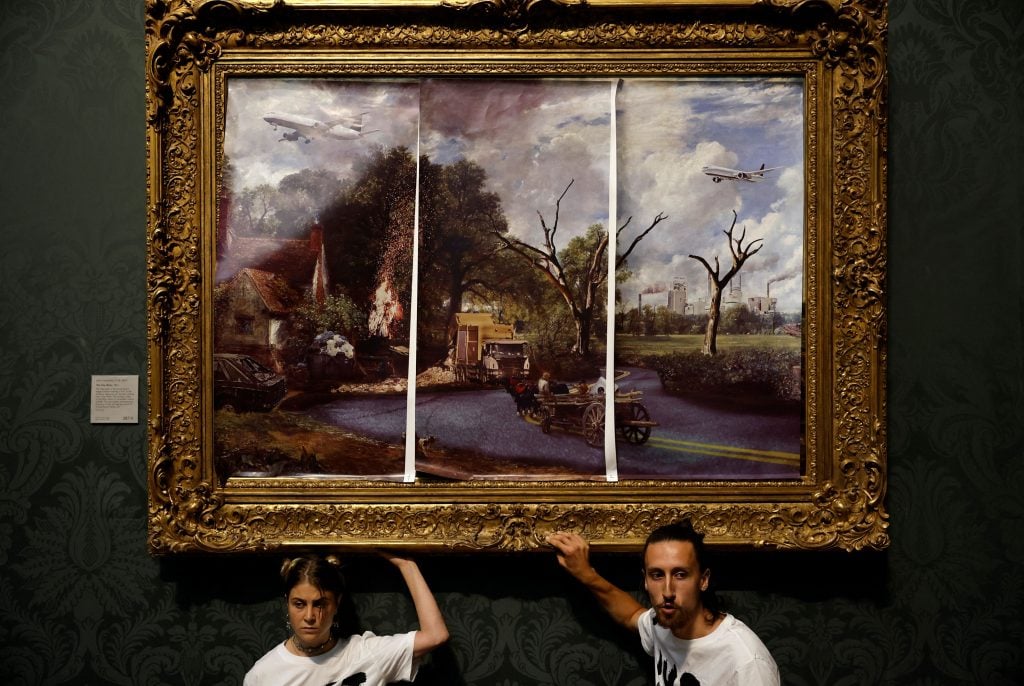 Activists from Just Stop Oil glued their hands to the frame of the painting The Hay Wain by English artist John Constable and covered it in a mock 'undated' version including roads and aircraft to protest against the use of fossil fuels at the National Gallery in London on July 4, 2022. (Photo by CARLOS JASSO/AFP via Getty Images)