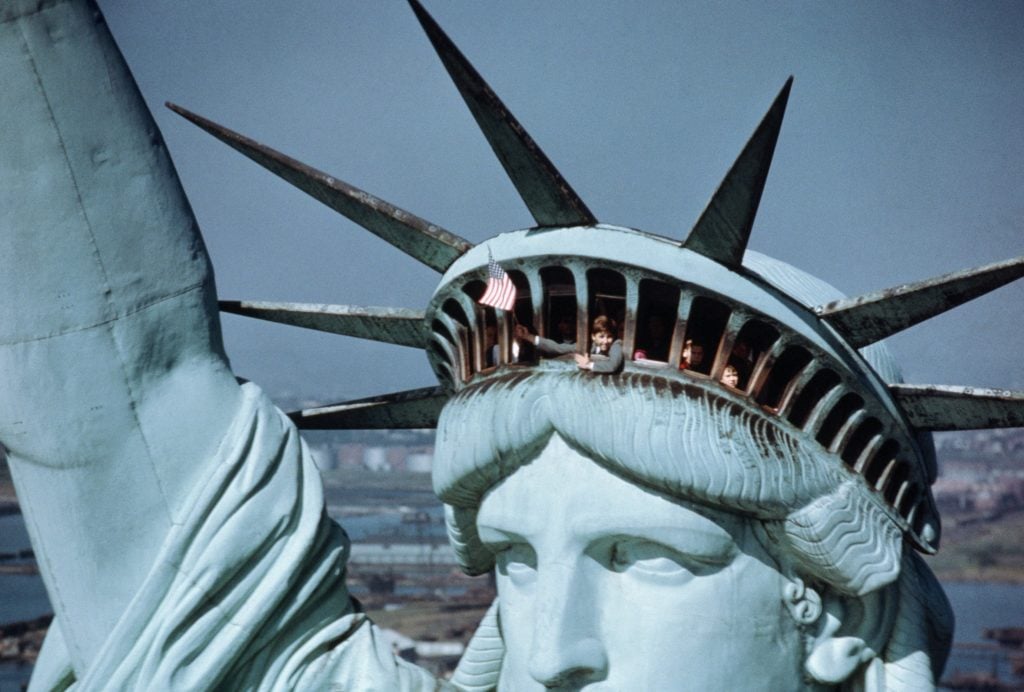 A child waves the United States flag from the crown of Frédéric Auguste Bartholdi's Liberty Enlightening the World, less formally known as the Statue of Liberty, on Liberty Island in New York Harbor. Photo from the Bettmann archive, courtesy of Getty Images.