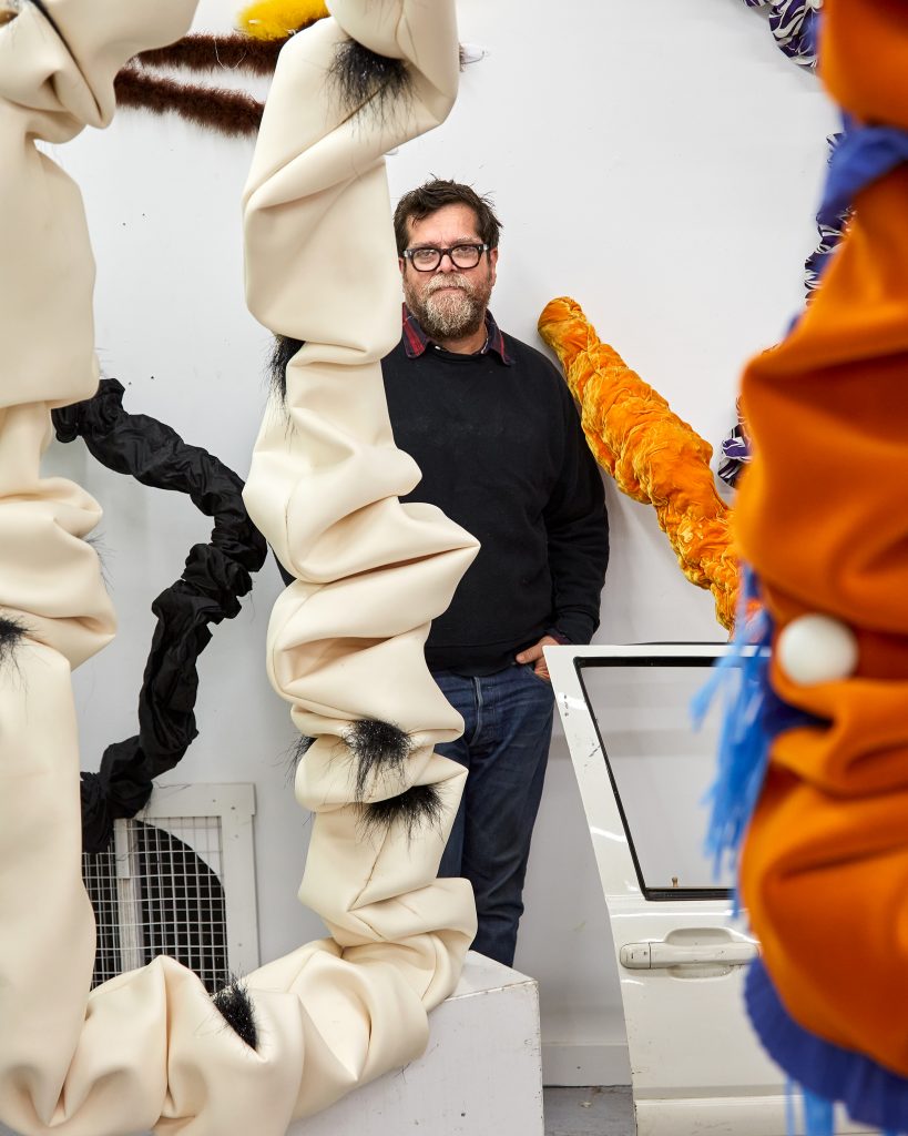 The artist Andy Harman orbited by his scrunchy sculptures and a Cheeto. Photo by Vincent Dilio.