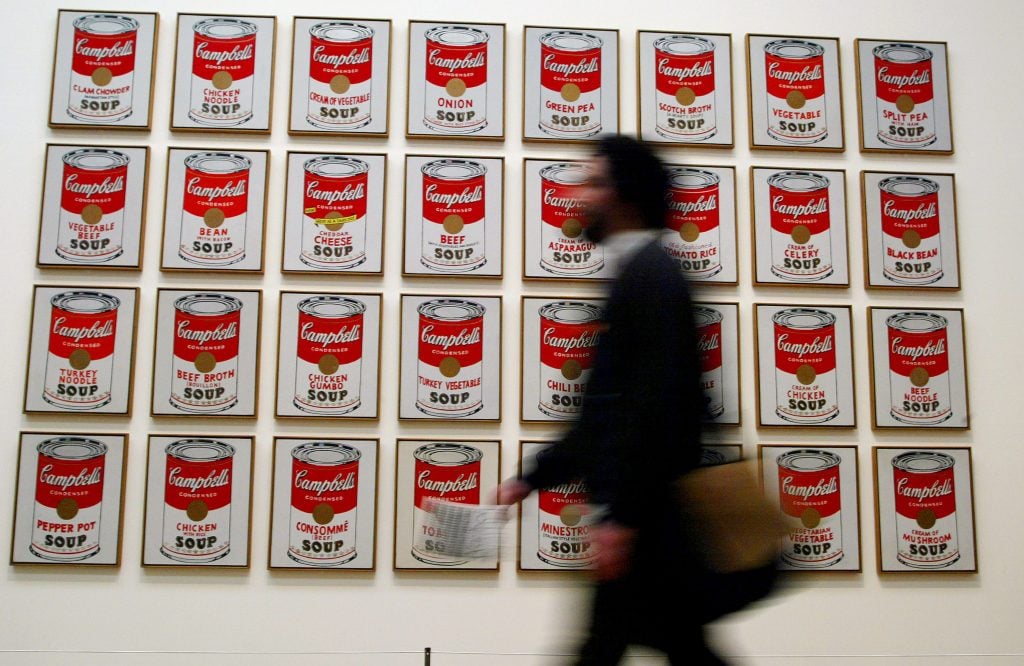 A spectator walks past Andy Warhol's Campbell's Soup Cans (1962) on February 5, 2002 at the Tate Modern Gallery in London. (Photo by Sion Touhig/Getty Images)