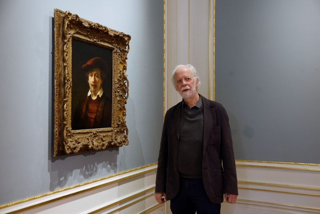 Dutch Rembrandt specialist Gary Schwartz poses next to <em>Rembrandt in a Red Beret</em>, either by Rembrandt van Rijn or his studio, at the Escher in Het Paleis in the Hague. Photo by Bas Czerwinski/ANP/AFP via Getty Images.