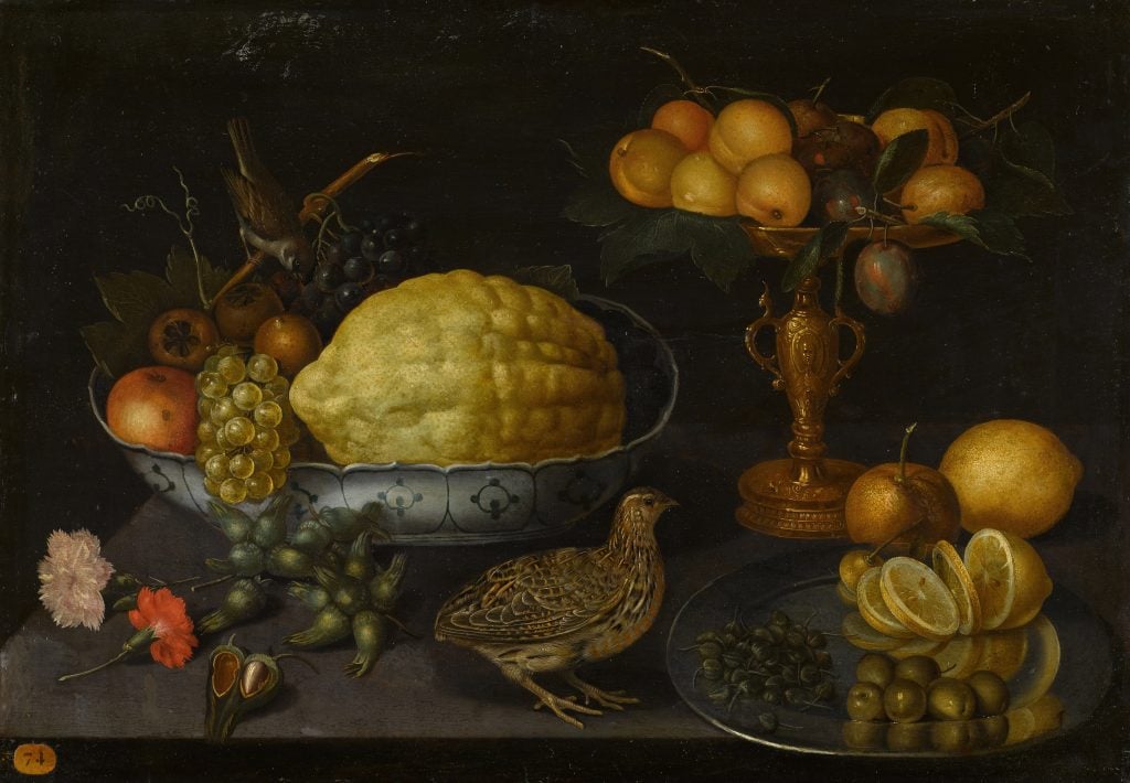 Peter Binoit, <i>Still life of a citron, grapes, an apple and other fruits in a porcelain bowl with a sparrow, with plums and apricots in a gilt tazza and a sliced lemon, olives and capers on a salver, with hazelnuts, flowers and a quail, all upon a ledge</i> (ca. early 17th century). Courtesy of Sotheby's.