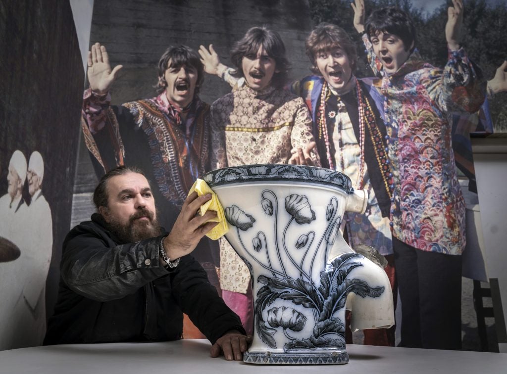 Roag Best gives a final polish to John Lennon's toilet, ahead of the item going on display at the Liverpool Beatles Museum. Photo by Danny Lawson/PA Images via Getty Images.