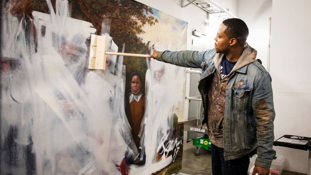 Titus Kaphar whitewashes a painting in Shut Up and Paint. Photo: Bret Hartman / TED.
