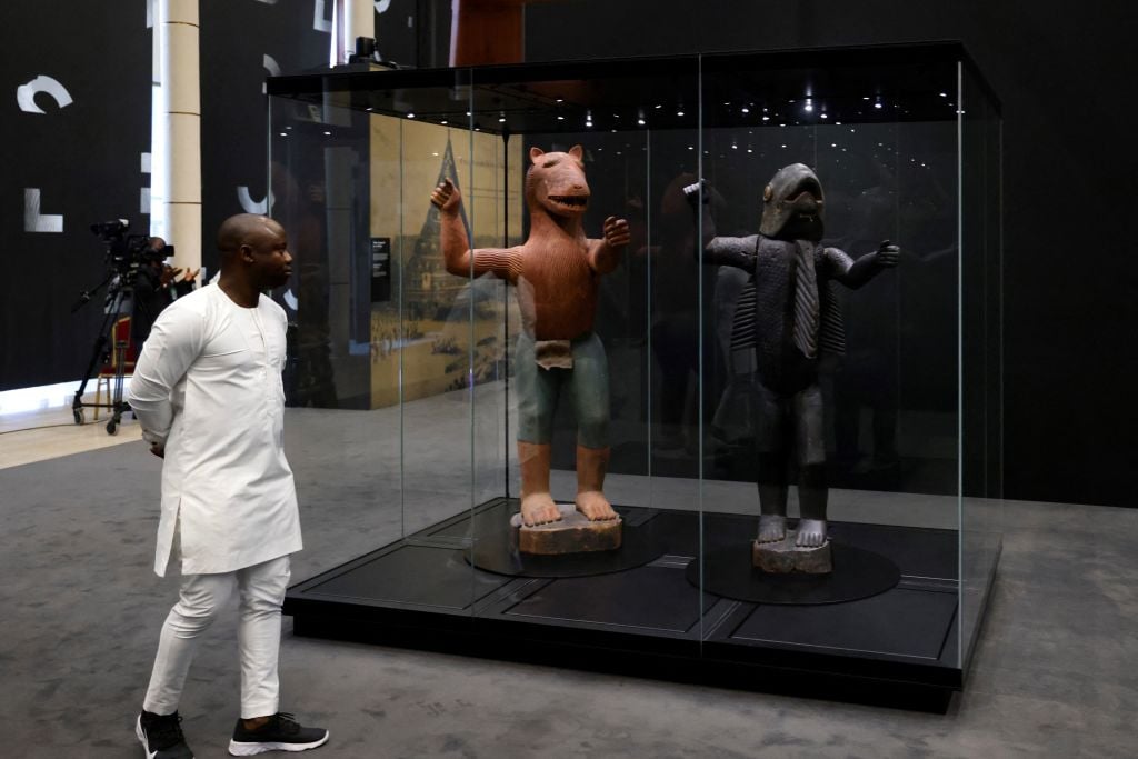 A visitor goes through the exhibition "Art of Benin of yesterday and today: from Restitution to Revelation" at the Marina Palace of Cotonou on July 27, 2022. Photo: Ludovic Marin/AFP via Getty Images