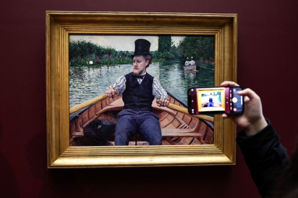 A man takes a picture of the painting 