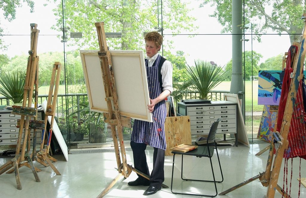 Prince Harry paints in the drawing room at Eton College on May 12, 2003 in Windsor, England. The Royal Family on October 9, 2004, denied allegations that the prince had cheated in his art A-level. Sarah Forsyth, a former teacher of Harry at Eton, made the allegations as she prepared to take the college to an industrial tribunal claiming for unfair dismissal. Photo by Anwar Hussein/Getty Images.