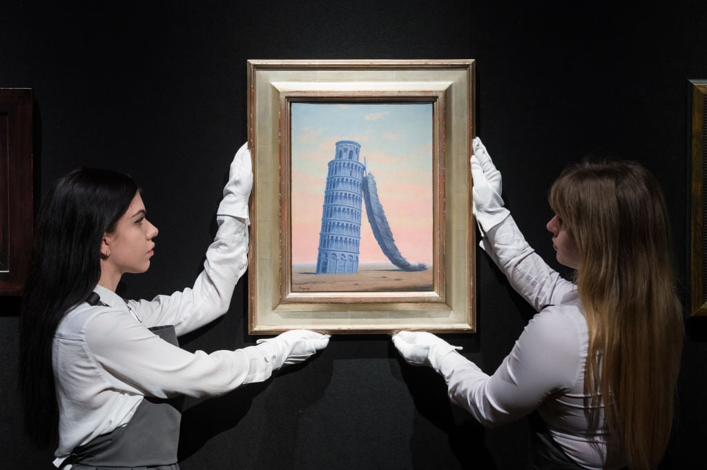 Art handlers hold a painting titled Souvenir de Voyage by Rene Magritte, estimate: £2,500,000-3,500,000 during a photo call for the upcoming 20th/21st Century Evening Sale and The Art of the Surreal Evening Sale in London, United Kingdom on February 21, 2023. Photo credit should read Wiktor Szymanowicz/Future Publishing via Getty Images.