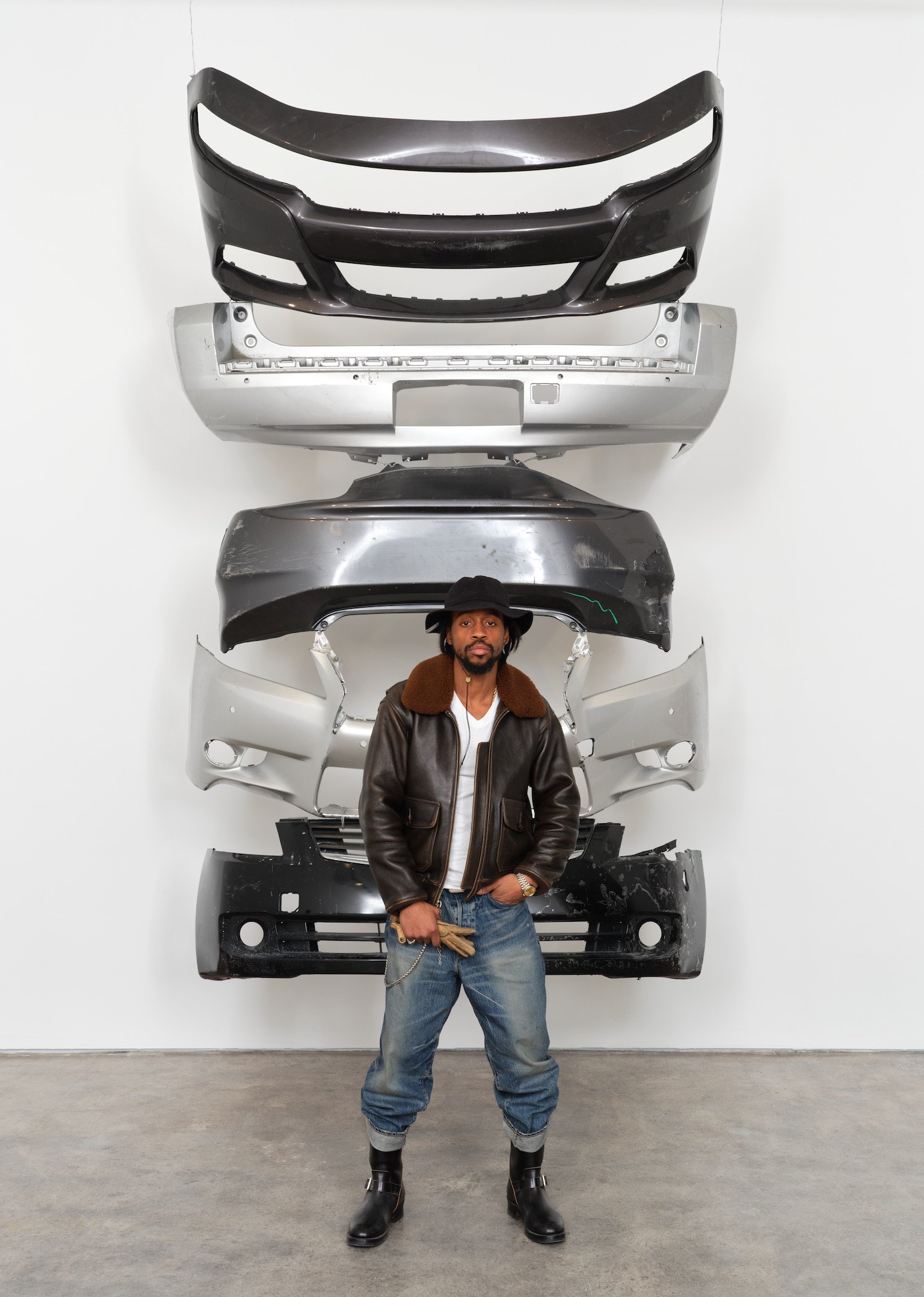 Daniel Tyree Gaitor-Lomack in front of A Stack of Dirty Car Bumpers, 2023. Photo: Nik Massey.