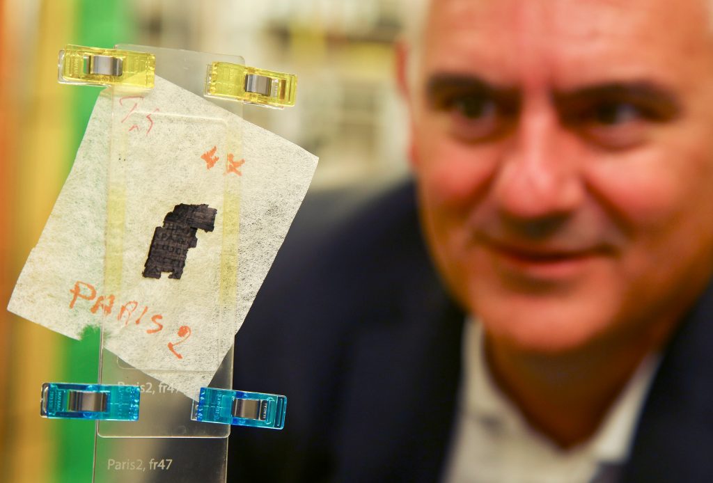 Brent Seales, director of the Digital Restoration Initiative at the University of Kentucky, examines a piece of Herculaneum scroll that was scanned at Diamond Light Source in Didcot, west of London. Researchers have been using the UK's national synchrotron science facility, Diamond Light Source, to examine fragments of 2,000 year-old of Herculaneum scroll, owned by the Institut de France, in the hope of using the high energy X-ray beamline to decode the fragments of scrolls. Photo by Geoff Caddick/AFP via Getty Images.