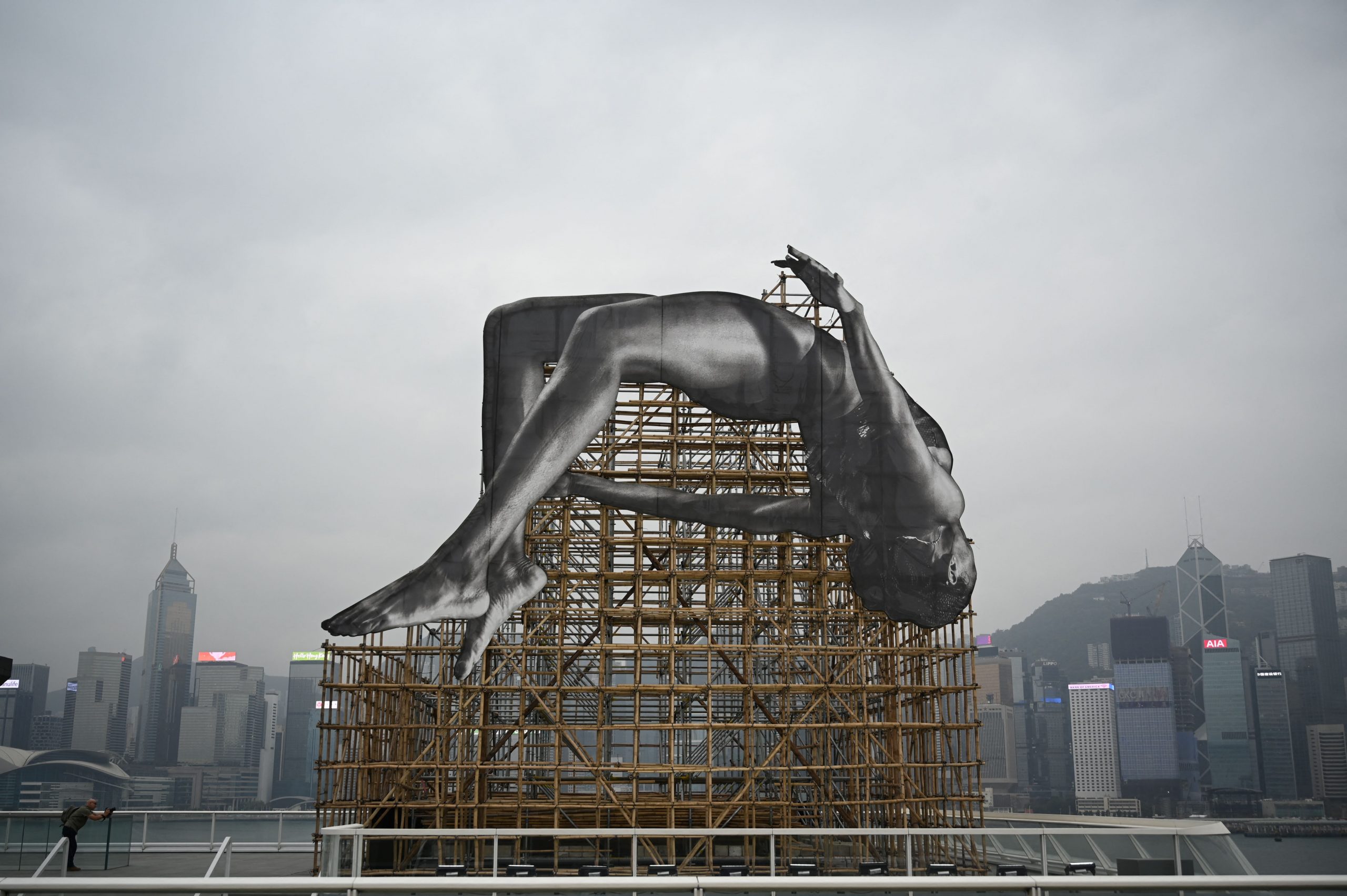 An installation by renowned French artist JR titled "GIANTS: Rising Up" is seen at a media preview in Hong Kong on March 13, 2023, depicting a larger-than-life high jumper adjacent to Hong Kong's Victoria Harbour. Photo by PETER PARKS/AFP via Getty Images.