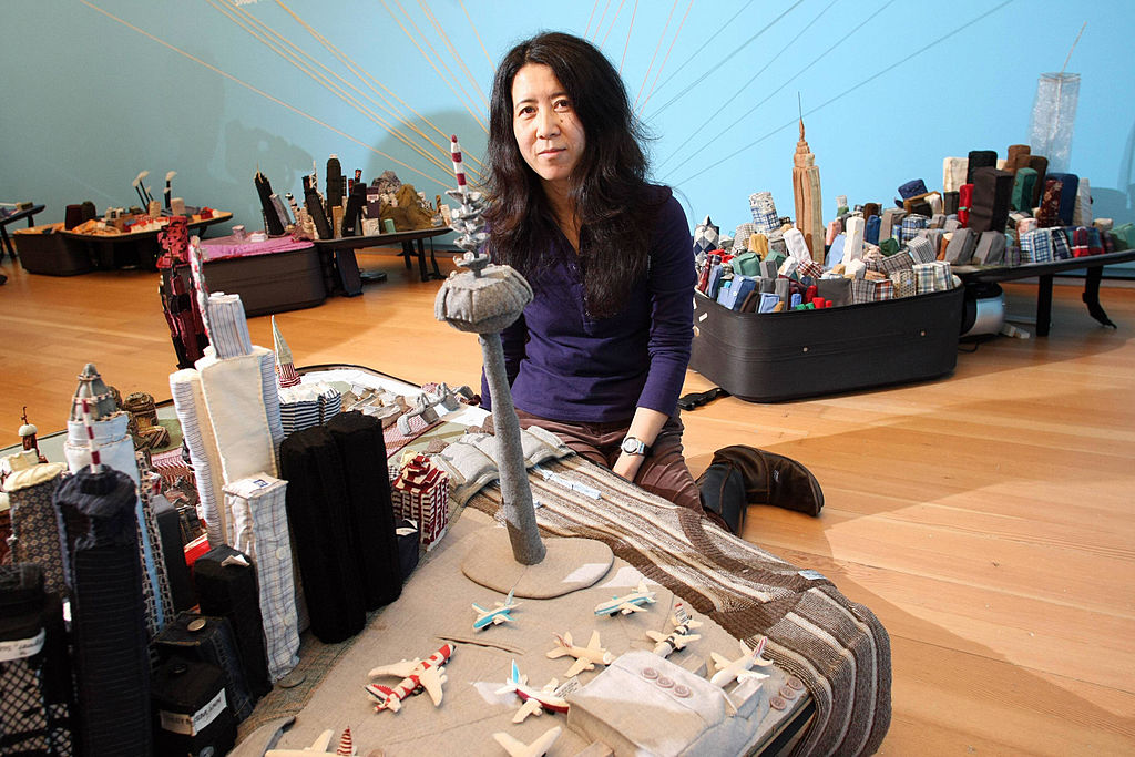 Chinese artist Yin Xiuzhen sits in front of her suitcase installation "Frankfurt (2007)." Photo by Thomas Lohnes/DDP/AFP via Getty Images.
